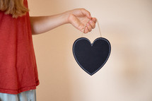 a girl holding a black heart chalkboard 