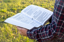 man reading the Bible outdoors 