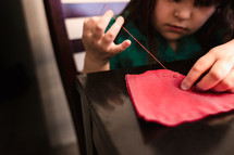 a child sewing with needle and thread 