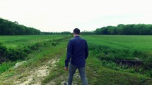 a man walking on a path through a field outdoors 