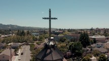 A dark metal cross on top of a Catholic church