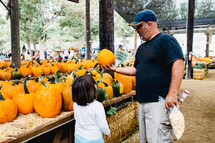 father and daughter picking out a pumpkin 
