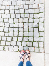 feet in sandals and cobblestone sidewalk 