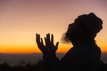 Silhouette of man praying during sunset