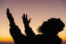 Silhouette of man praying during sunset