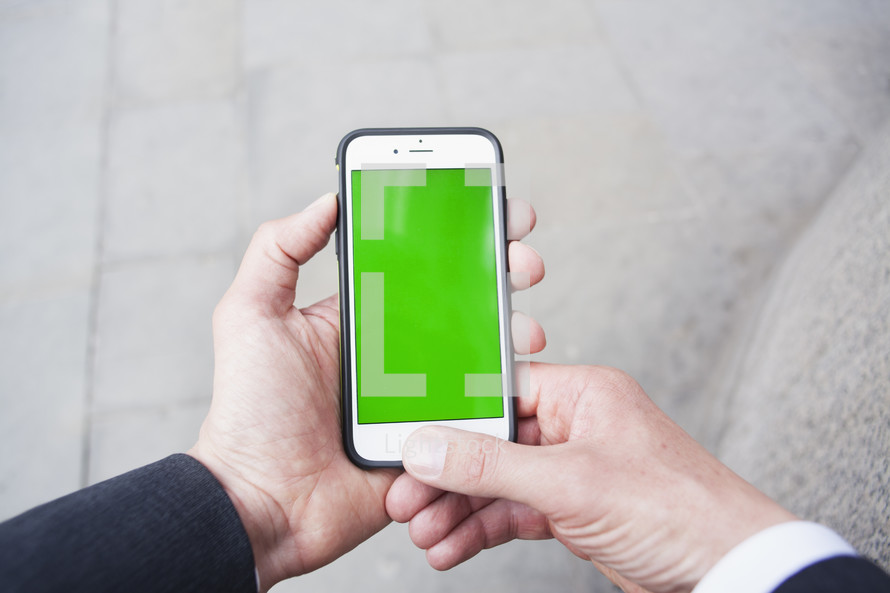 Personal perspective of a man using a smartphone with a green screen- for editorial use only 