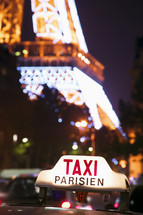 Taxi cab sign in from of the Eiffel Tower at night. Paris, France. - for editorial use only.