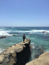 man standing on a rock over the ocean 