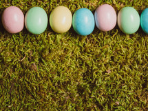 A line of colorful Easter eggs on green grass.