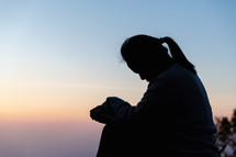 Silhouette of woman praying during sunset