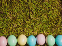 A line of colorful eggs on green grass.