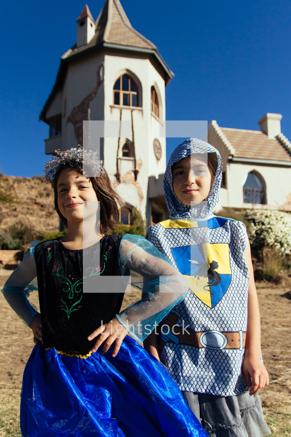 kids dressed up as a knight and princess standing in front of a castle 