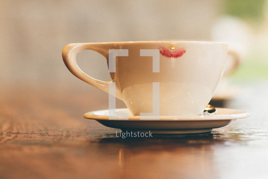 A cup and saucer with a lipstick mark.