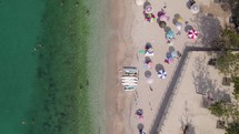 Topdown ascending view of Beach shoreline with emerald colored water, Colorful sun hats in white sand beach, Himare