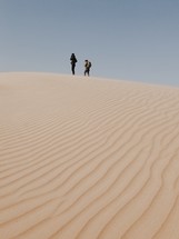 men standing at the top of a sand dune 