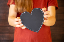 girl holding a blank black heart 