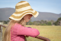 woman in straw hat leaning on gate
