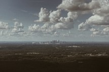 distant city under white puffy clouds 