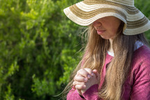 praying girl in a straw hat 