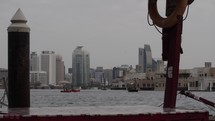 Boats and birds flying with distant buildings in Old Dubai river in cinematic slow motion.