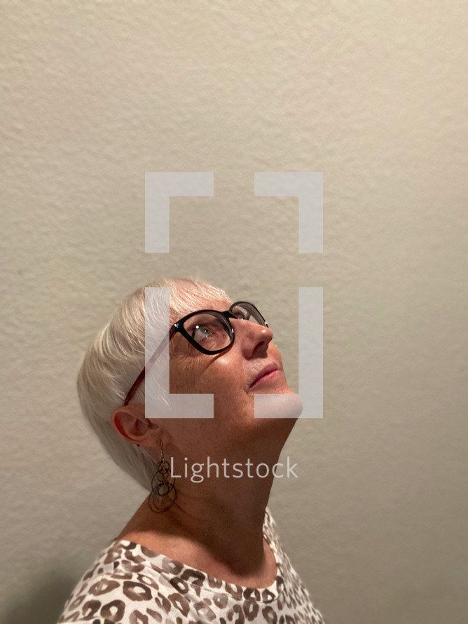 woman with glasses and short hair looking upward, 3/4 view of face, lit from above (self-portrait)