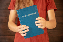 a girl holding a Baptist Hymnal 