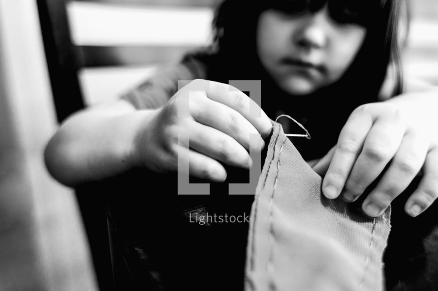 a child sewing with a needle and thread