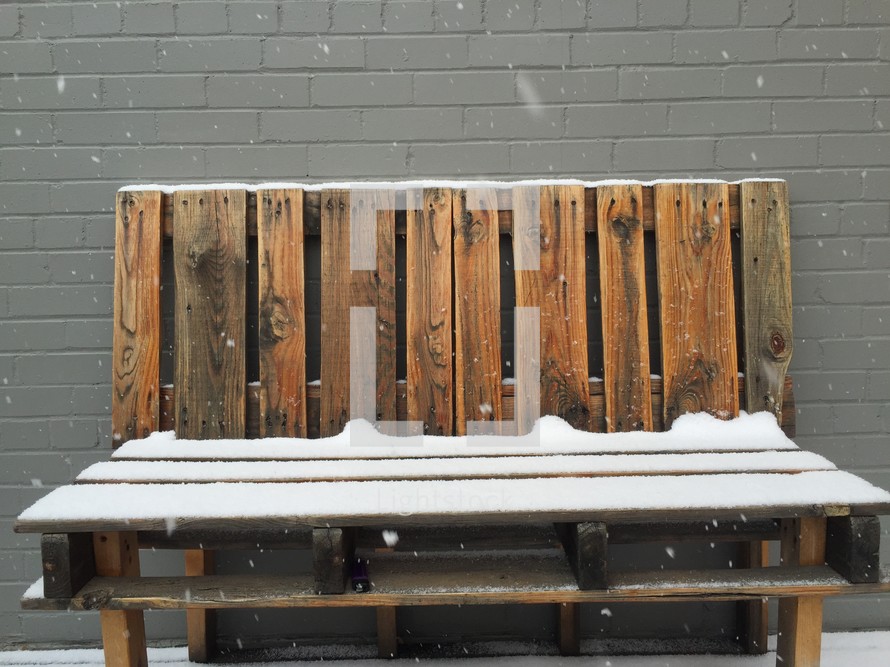 snow on a bench made of pallets 