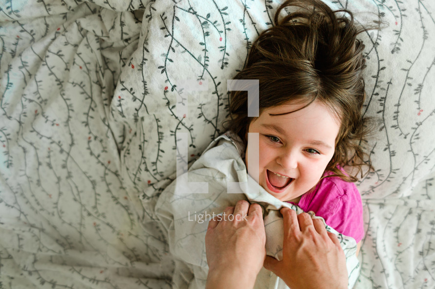 A laughing little girl being tickled by her father.