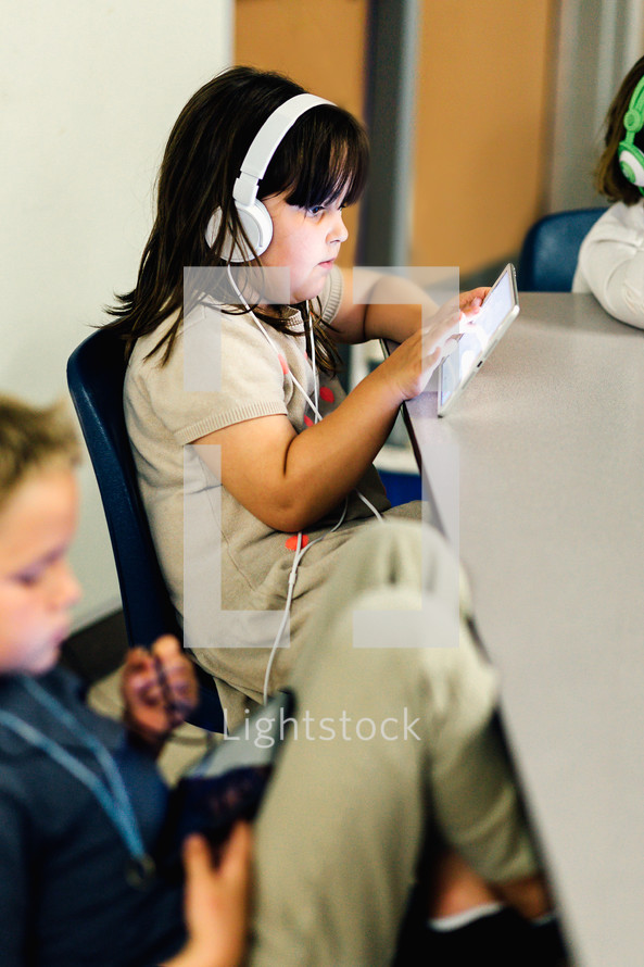 a child with headphones using a tablet in a classroom 