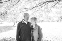 an elderly couple standing outdoors in fall 
