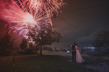 fireworks bursting in the night sky over a bride and groom 