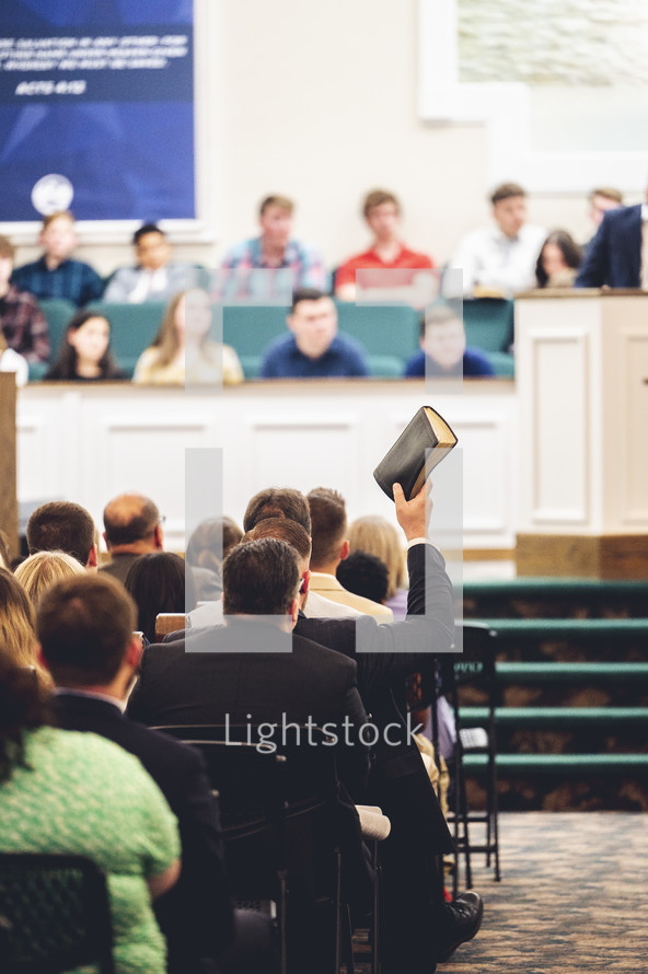 man holding up a Bible at church 