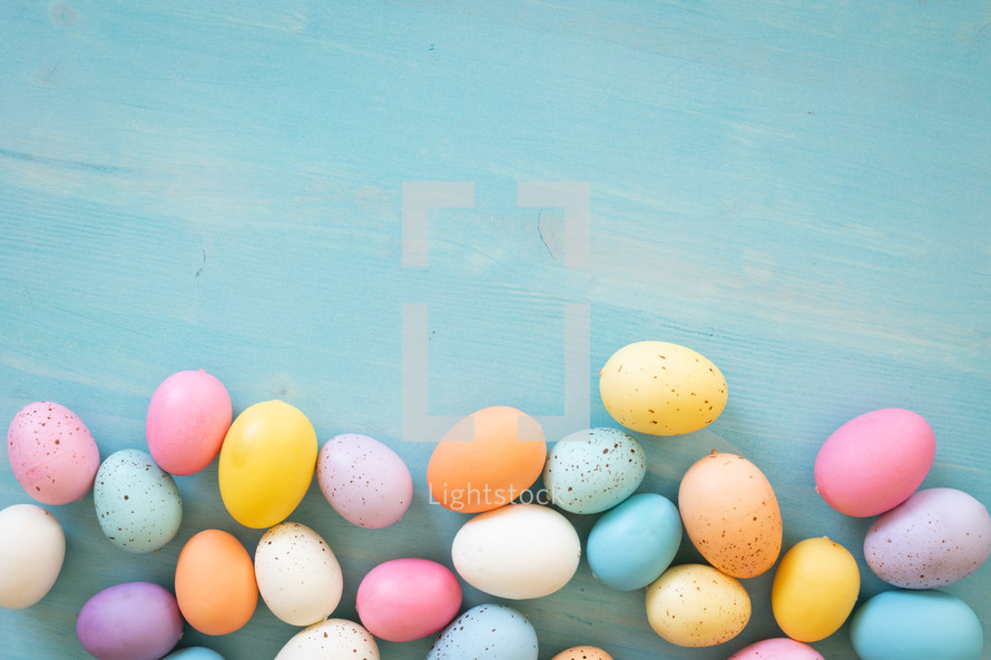 Border of easter eggs on a blue wood background with copy space