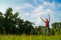 girl with hands raised standing outdoors 