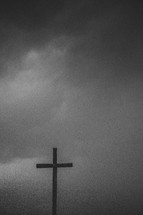 Silhouette of a wooden cross under a stormy sky.