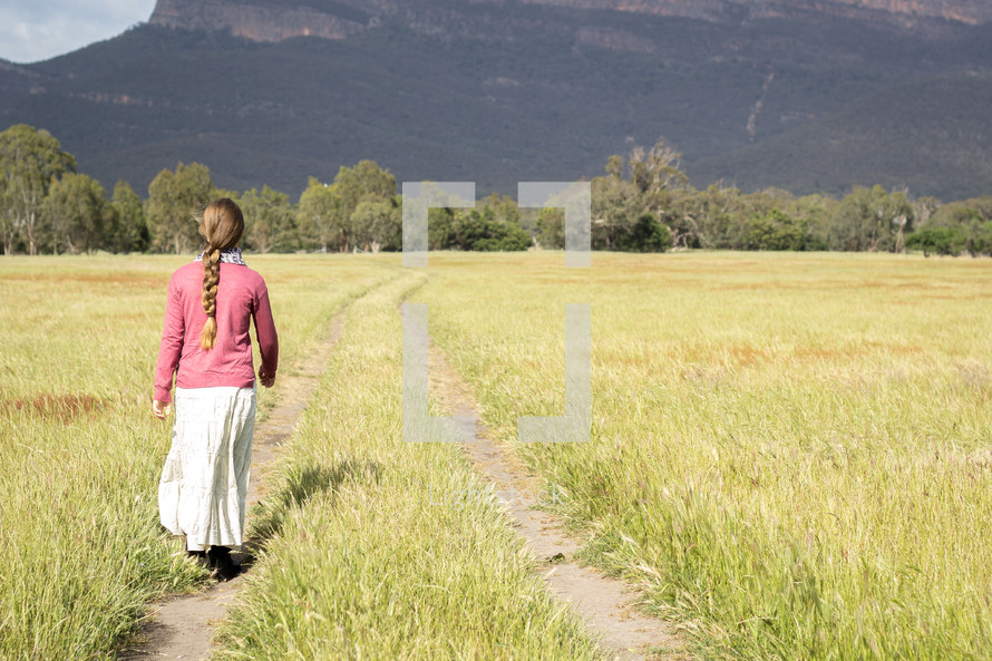 teen girl walking in a field 