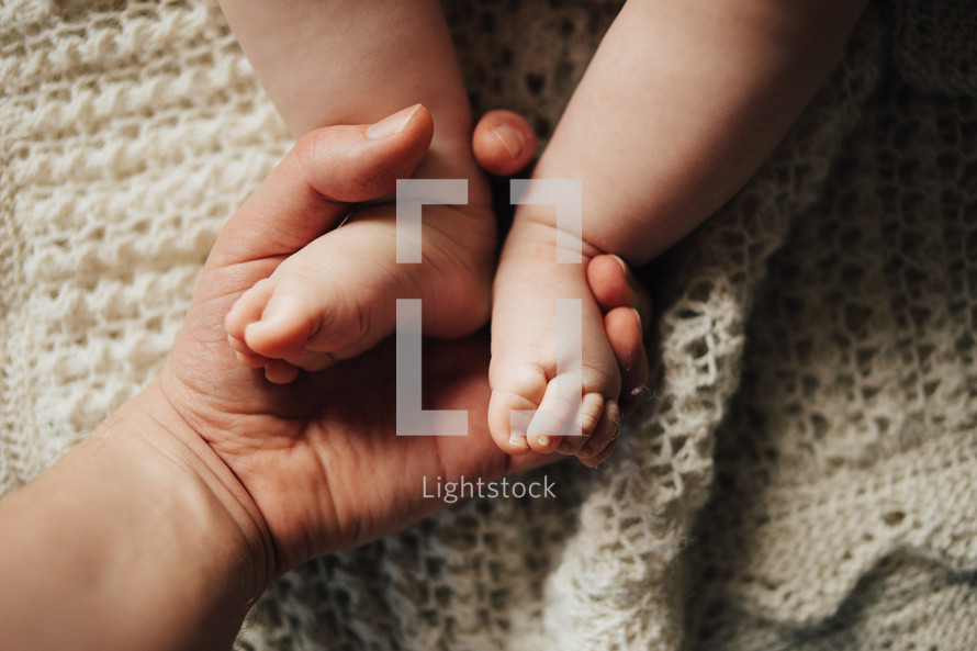 a mother holding a newborns feet 