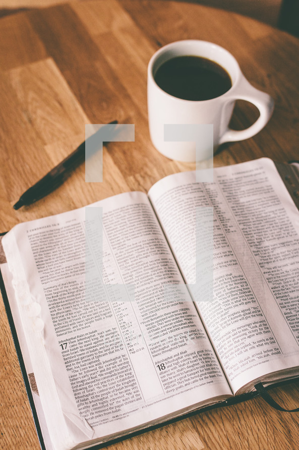 An open Bible and a cup of coffee on a table.