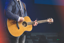 Worship leader in suit with an acoustic guitar