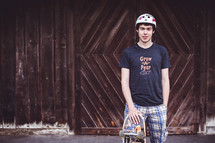 a young man in a helmet holding a skateboard 