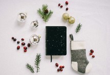 Bible in the snow with a spruce twig, red berries, sock, gold ornaments 