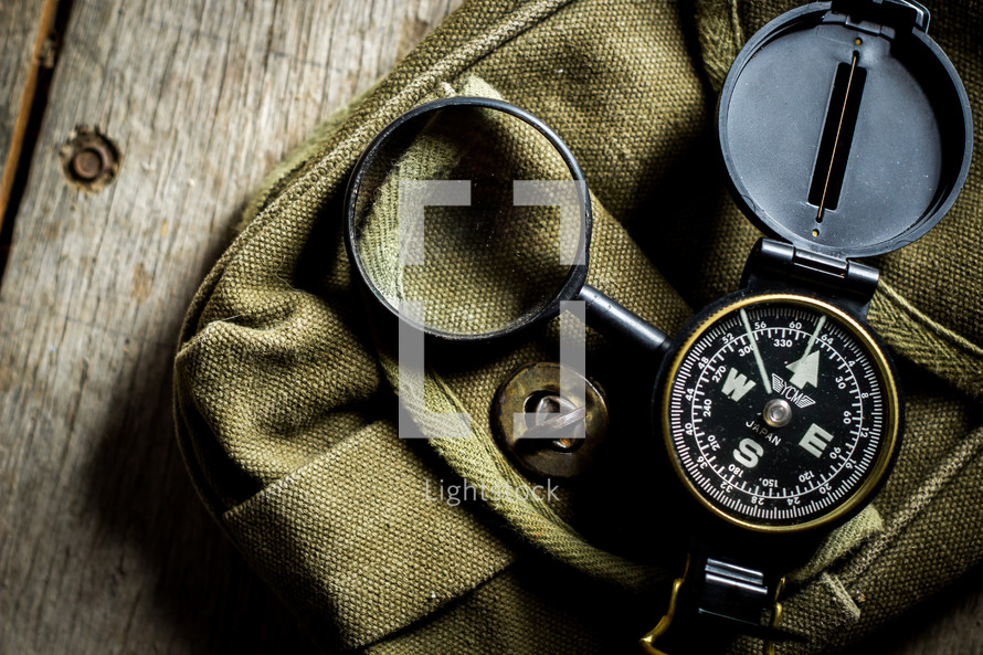 compass and magnifying glass on a green bag 