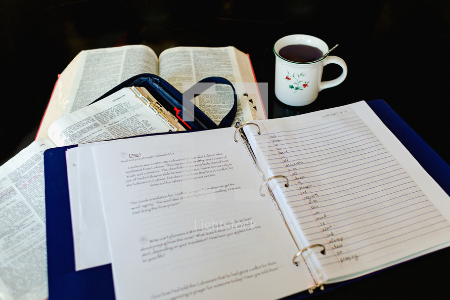 a list in a three ring notebook and an open Bible 