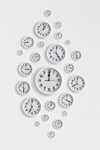 Many round clocks on a white wall.