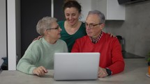Daughter and senior parents together bonding in front the laptop.