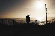 Couple embracing on beach at sunset.