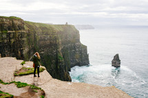 a woman standing at the edge of the Cliffs of Moher 