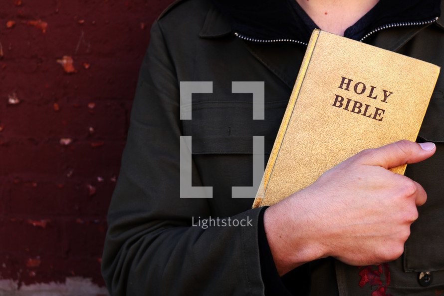 a man holding a Bible against his chest 