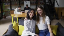 A girl and her female mentor in white blouses pose for the camera.